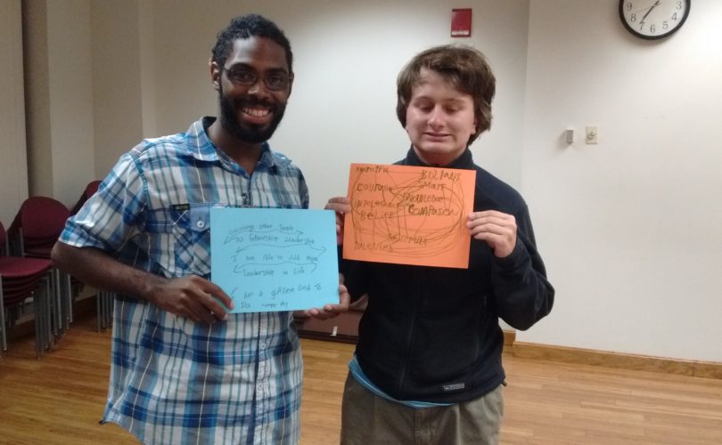 Two young men holding signs about what mentoring means to them