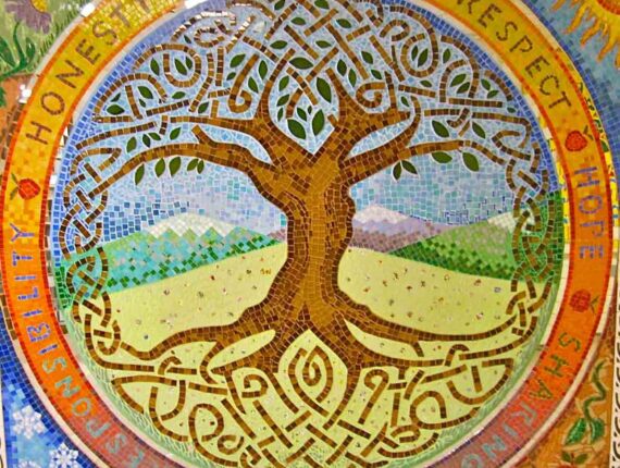 A mosaic of a tree with long intertwined roots and branches with mountains and grass in the background.