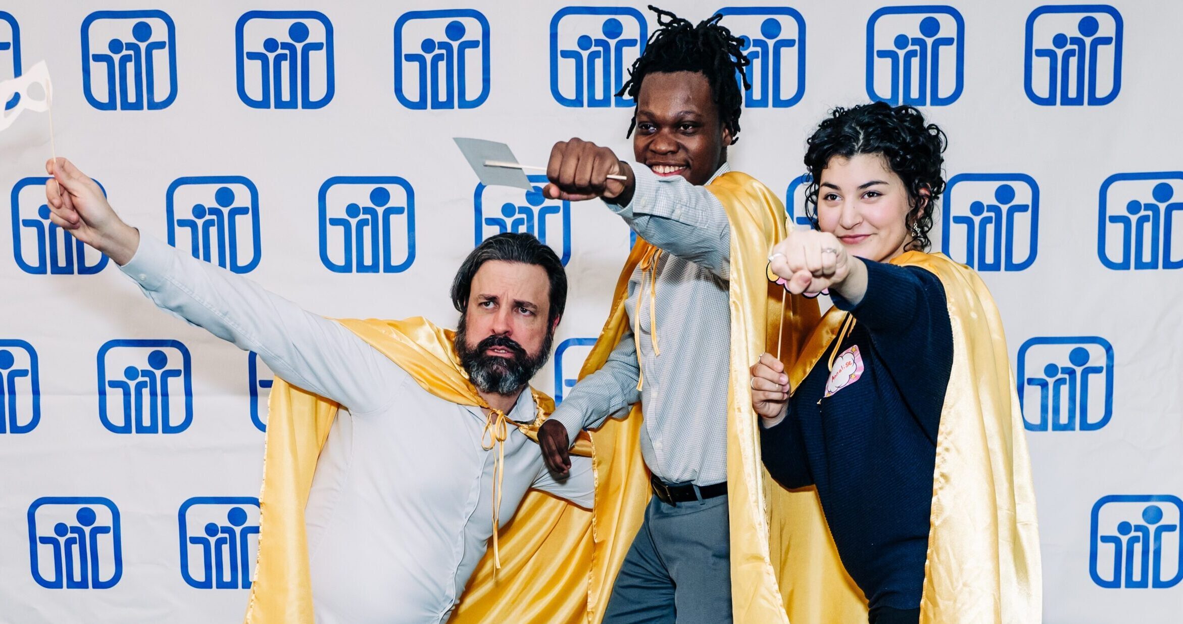 Three PYD 2024 Honors Night award recipients wearing gold capes and posing like superheroes!